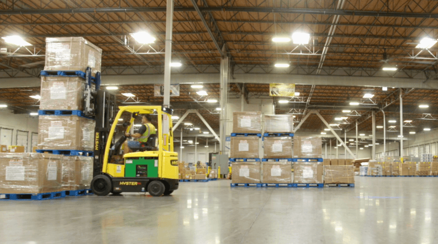 A forklift truck in a warehouse with boxes on the ground, ready for transporting goods.