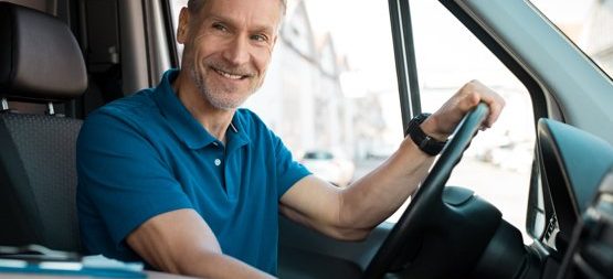 a truck driver sitting in driver seat smiling