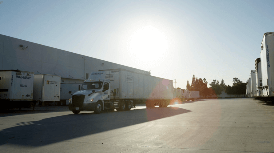 A large warehouse with trucks parked in front of it, ready for loading and unloading goods.