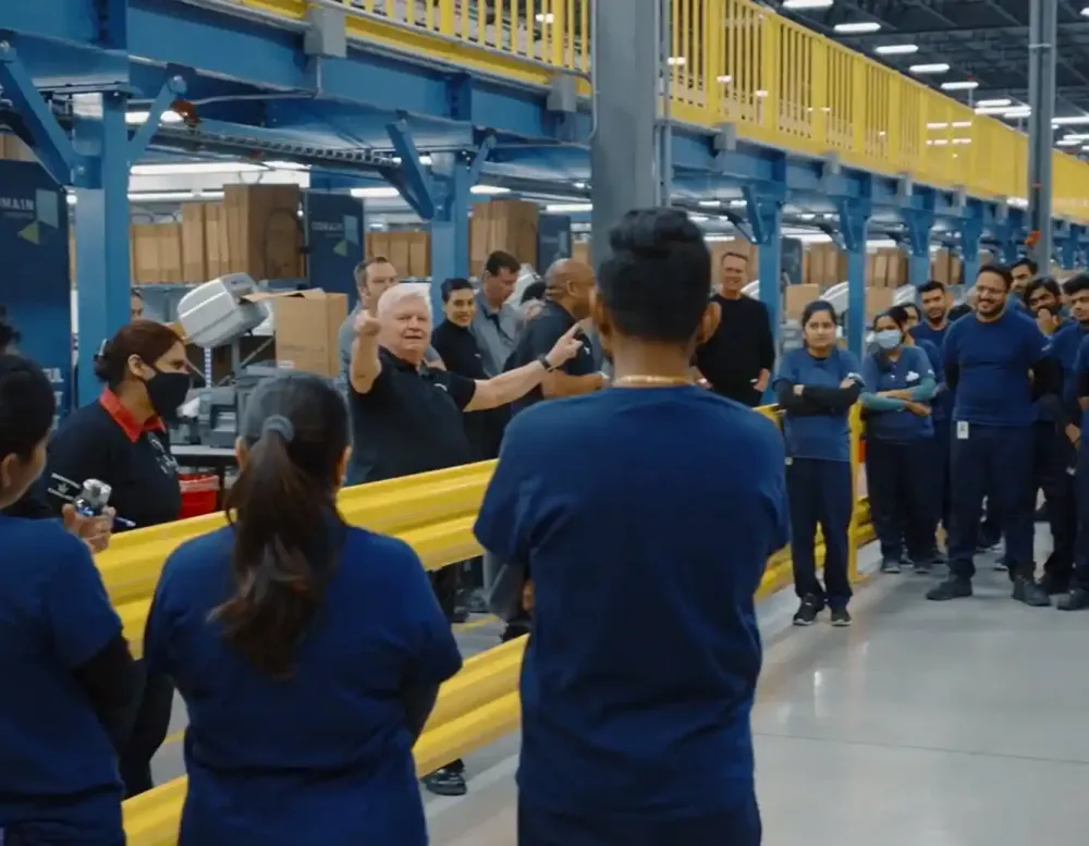 A manager speaking to employees in a warehouse.