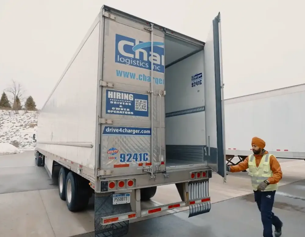 A truck driver closing the back of his semi truck.