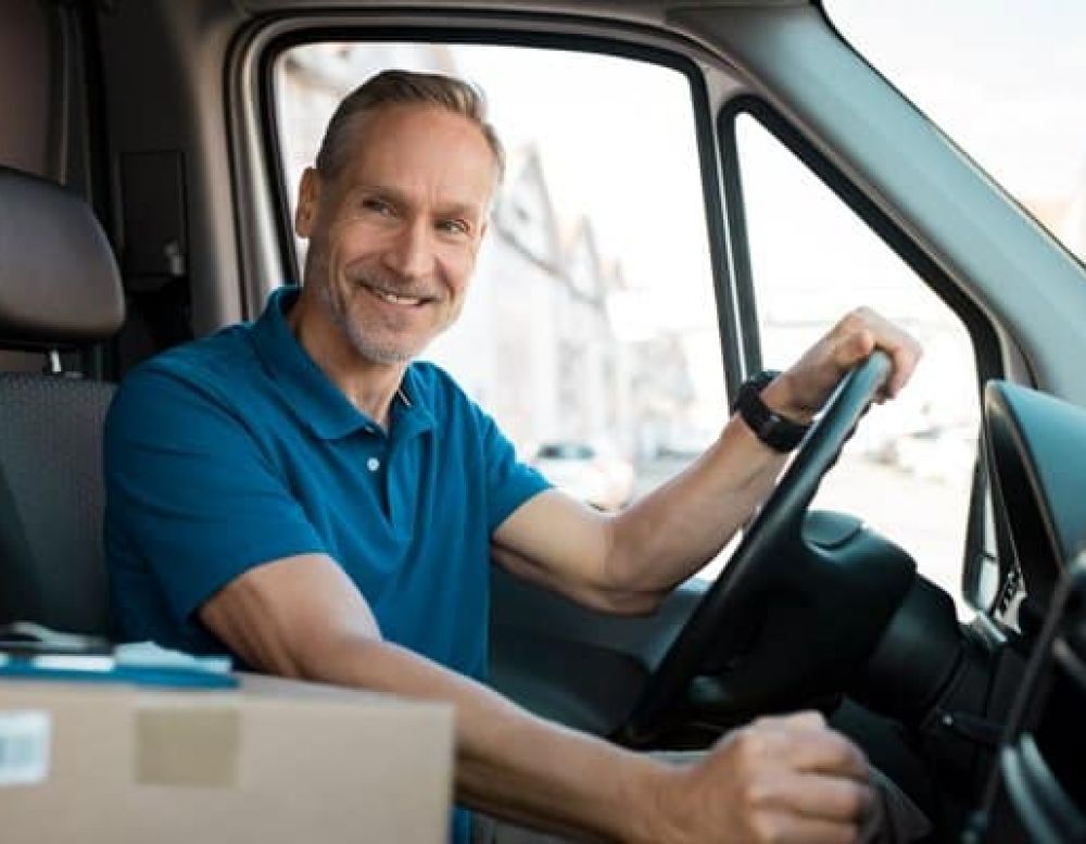 a truck driver sitting in driver seat smiling