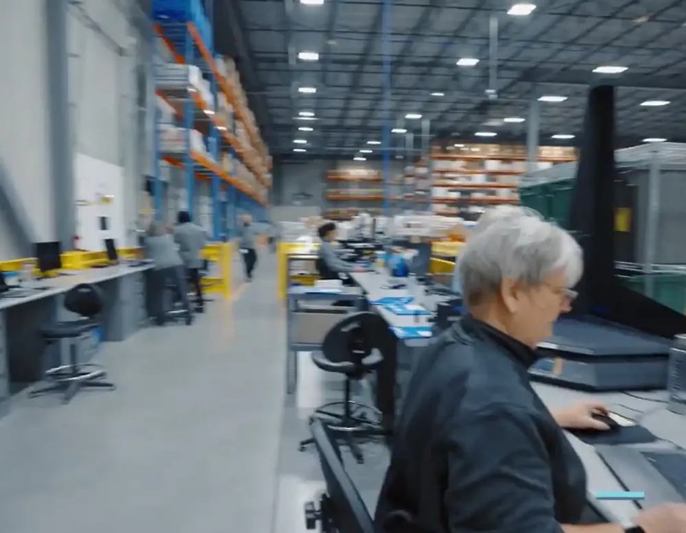 A worker at a computer station in a warehouse.