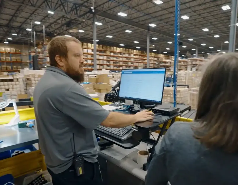 A worker at a computer in a warehouse.